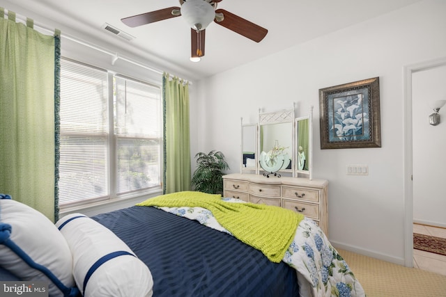 tiled bedroom with multiple windows and ceiling fan