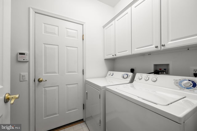 clothes washing area with cabinets and washer and dryer