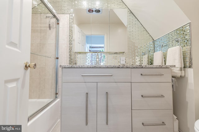 bathroom featuring enclosed tub / shower combo, vanity, and backsplash