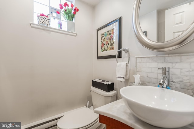 bathroom featuring toilet, sink, and a baseboard heating unit