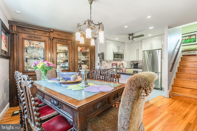 dining area featuring light wood-type flooring and ceiling fan with notable chandelier