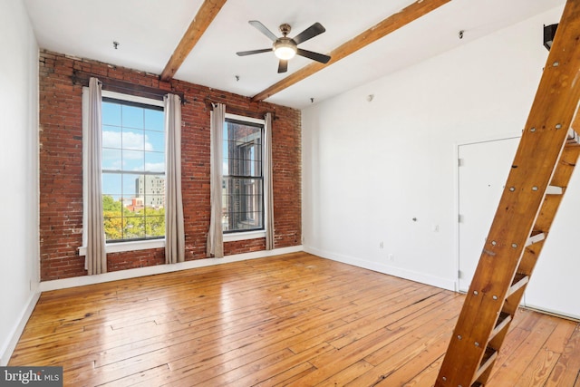 unfurnished bedroom featuring brick wall, beamed ceiling, and light hardwood / wood-style flooring