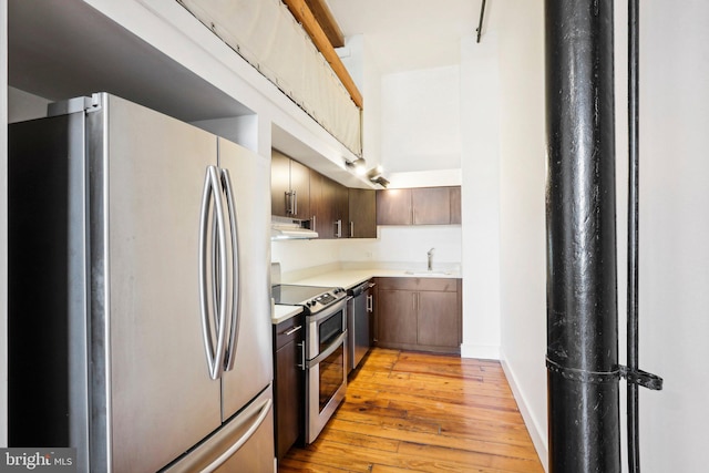 kitchen featuring dark brown cabinetry, light hardwood / wood-style floors, sink, and stainless steel appliances