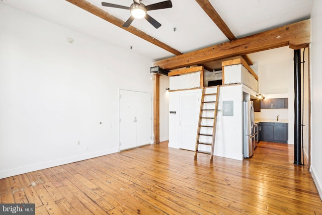 unfurnished living room with beamed ceiling, ceiling fan, light hardwood / wood-style flooring, and sink