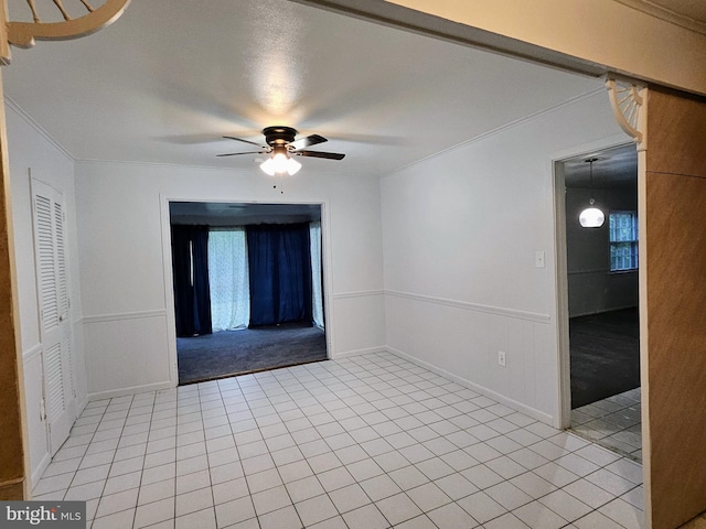 empty room featuring light tile patterned flooring, ornamental molding, and ceiling fan