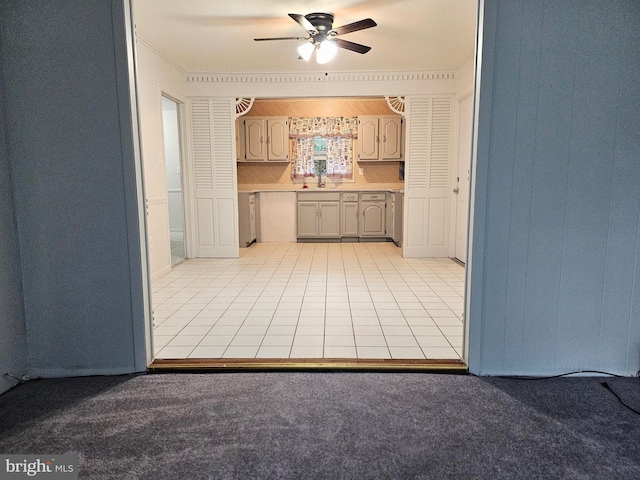 kitchen with crown molding, light colored carpet, gray cabinetry, and ceiling fan