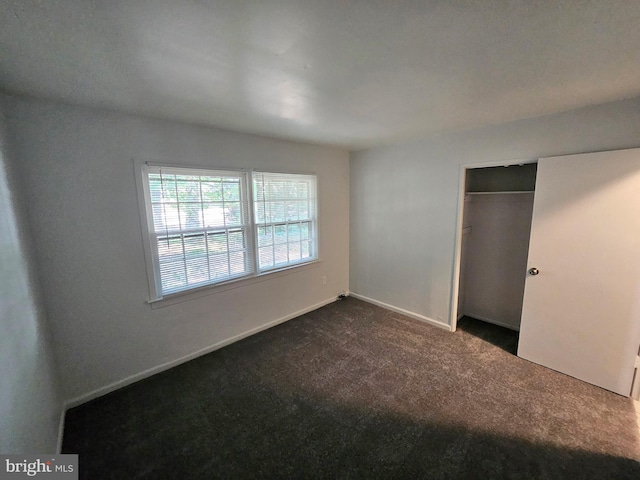 unfurnished bedroom with a closet and dark carpet