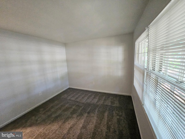 unfurnished room with dark colored carpet