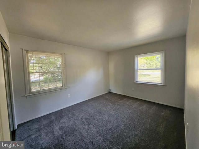 unfurnished room featuring dark carpet