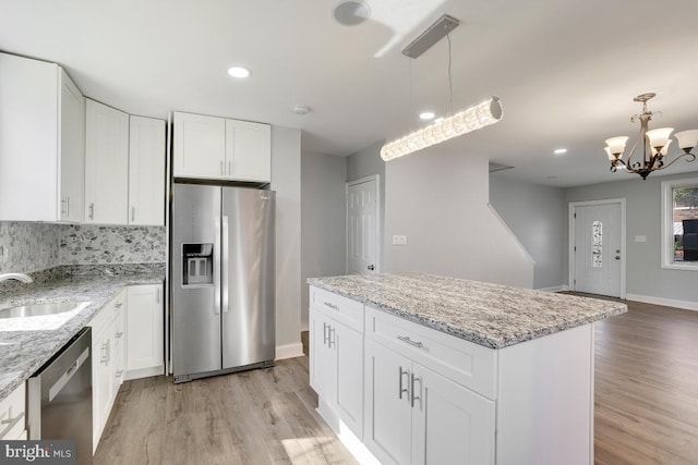 kitchen featuring a kitchen island, appliances with stainless steel finishes, light hardwood / wood-style floors, hanging light fixtures, and white cabinets