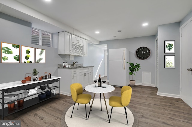 kitchen featuring white fridge, dark hardwood / wood-style floors, white cabinetry, and light stone countertops