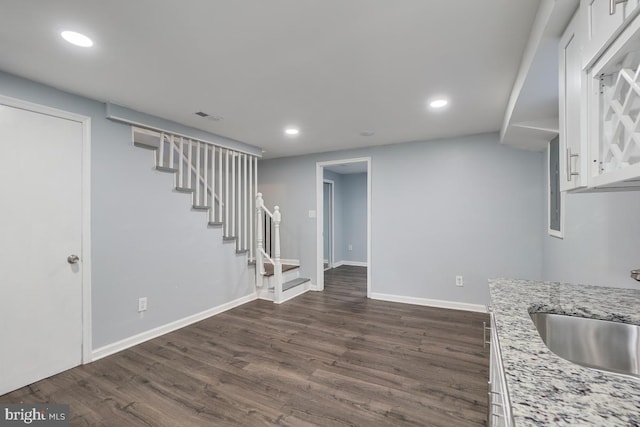 interior space with sink, light stone countertops, dark hardwood / wood-style flooring, and white cabinets