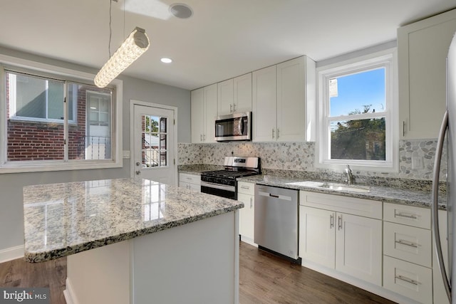 kitchen featuring white cabinetry, plenty of natural light, stainless steel appliances, and hanging light fixtures