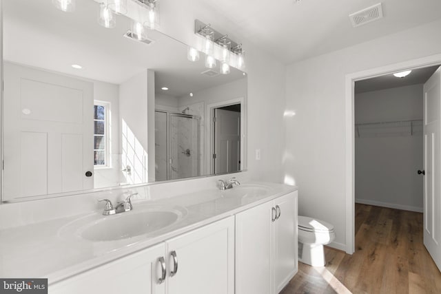 bathroom featuring vanity, wood-type flooring, toilet, and walk in shower