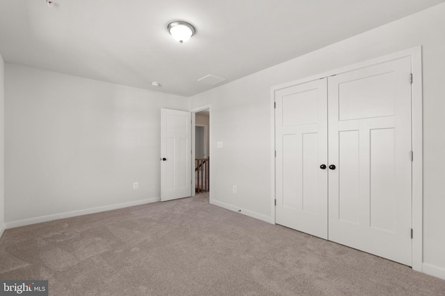 unfurnished bedroom featuring light colored carpet and a closet