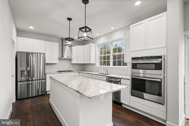 kitchen featuring hanging light fixtures, appliances with stainless steel finishes, dark hardwood / wood-style floors, wall chimney exhaust hood, and a center island