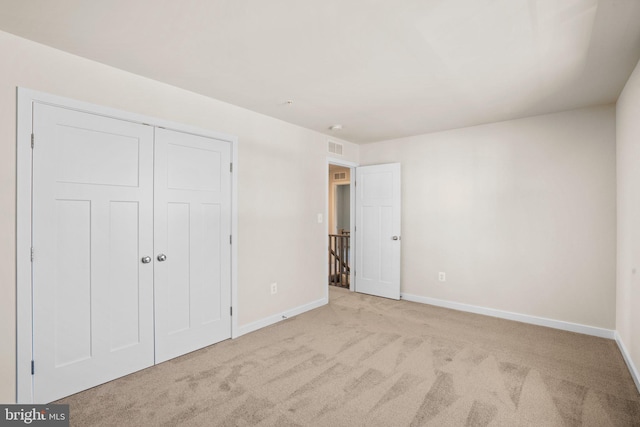 unfurnished bedroom featuring a closet and light colored carpet