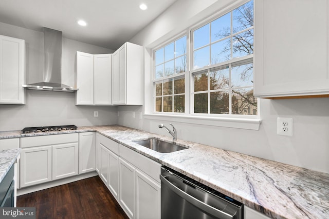 kitchen with wall chimney range hood, appliances with stainless steel finishes, white cabinetry, dark wood-type flooring, and sink