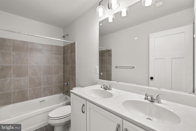 full bathroom featuring vanity, tiled shower / bath combo, and toilet