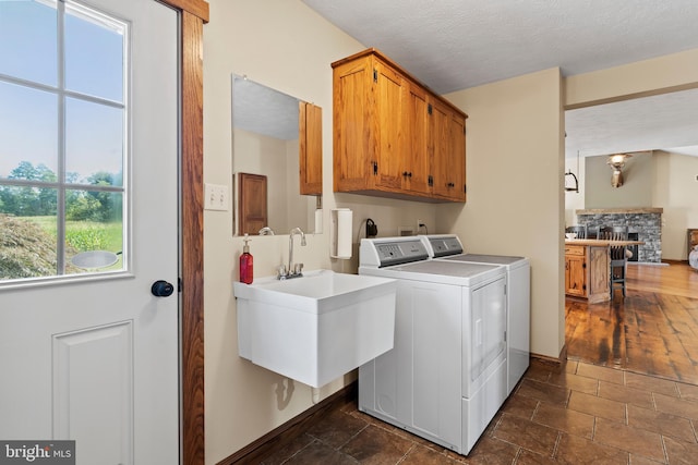 washroom featuring a stone fireplace, a textured ceiling, cabinets, separate washer and dryer, and dark hardwood / wood-style flooring