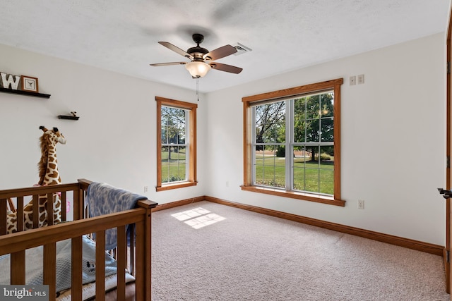 carpeted bedroom with multiple windows, a textured ceiling, and ceiling fan