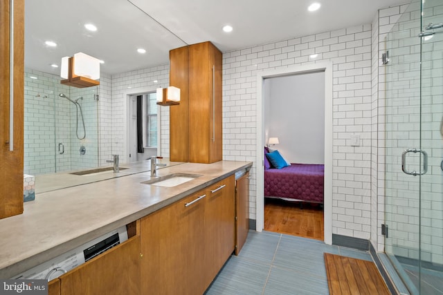 bathroom with tile walls, vanity, tile patterned floors, and a shower with shower door