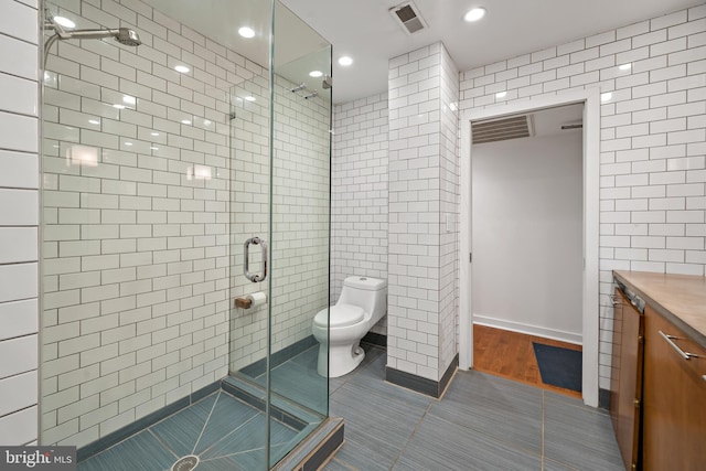 bathroom featuring vanity, tile walls, a shower with shower door, and toilet