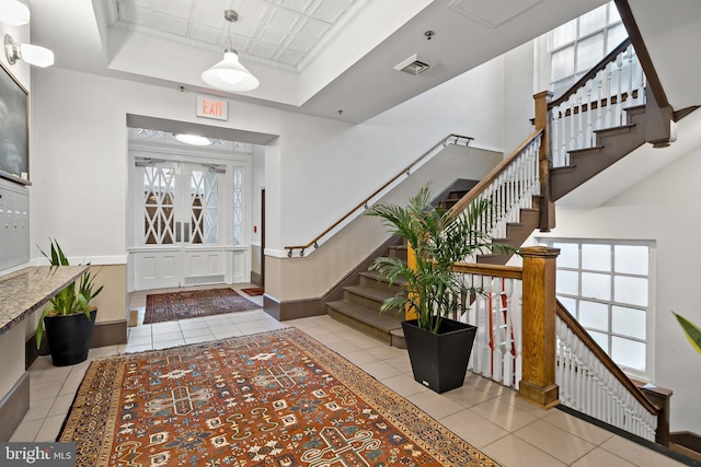 foyer entrance with a tray ceiling, light tile patterned floors, and a wealth of natural light