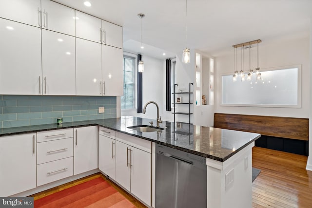 kitchen with hanging light fixtures, white cabinets, kitchen peninsula, dishwasher, and sink