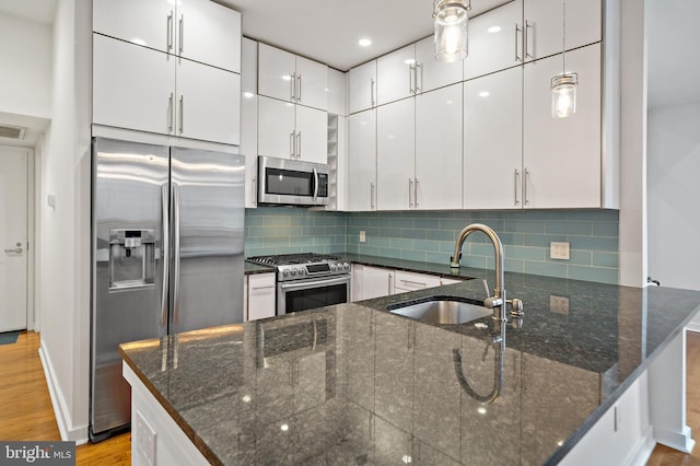 kitchen featuring hanging light fixtures, light hardwood / wood-style floors, white cabinetry, stainless steel appliances, and sink