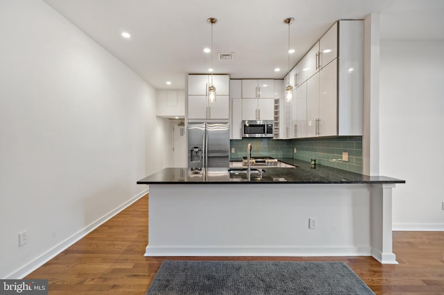 kitchen with hanging light fixtures, white cabinetry, kitchen peninsula, dark hardwood / wood-style flooring, and stainless steel appliances