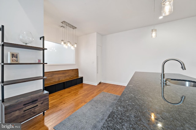 kitchen with light wood-type flooring, hanging light fixtures, and sink