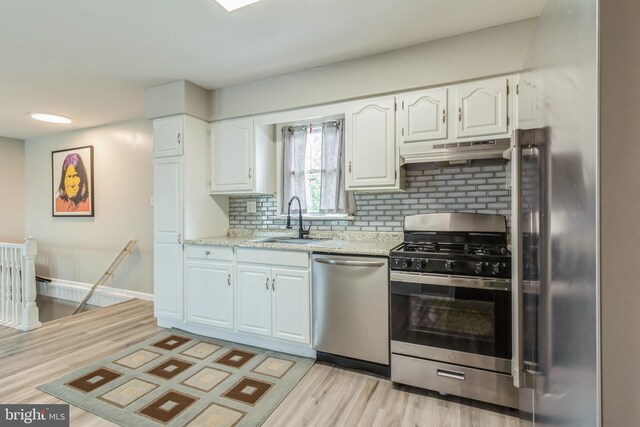 kitchen featuring sink, white cabinetry, stainless steel appliances, light wood-type flooring, and decorative backsplash