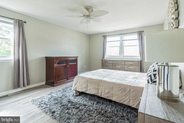 bedroom with multiple windows, light wood-type flooring, and ceiling fan