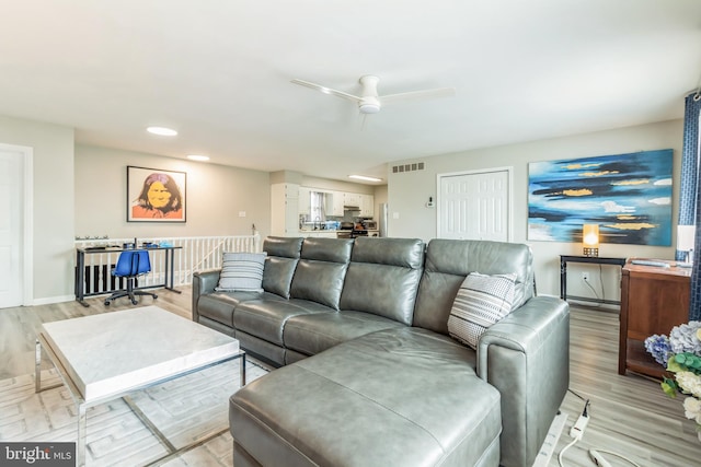 living room featuring light hardwood / wood-style flooring and ceiling fan