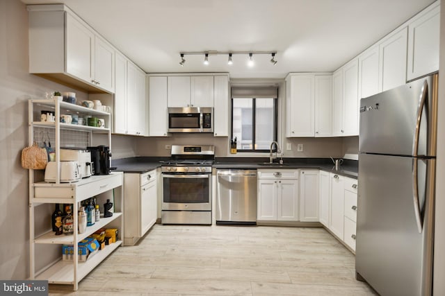 kitchen featuring stainless steel appliances, white cabinets, sink, and light hardwood / wood-style flooring