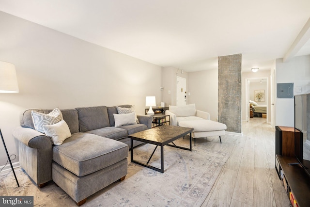 living room with light hardwood / wood-style floors, decorative columns, and electric panel