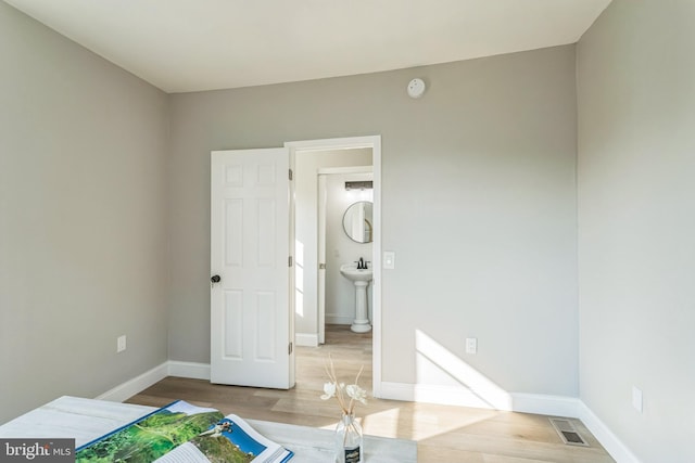 unfurnished bedroom featuring light wood-type flooring and ensuite bathroom