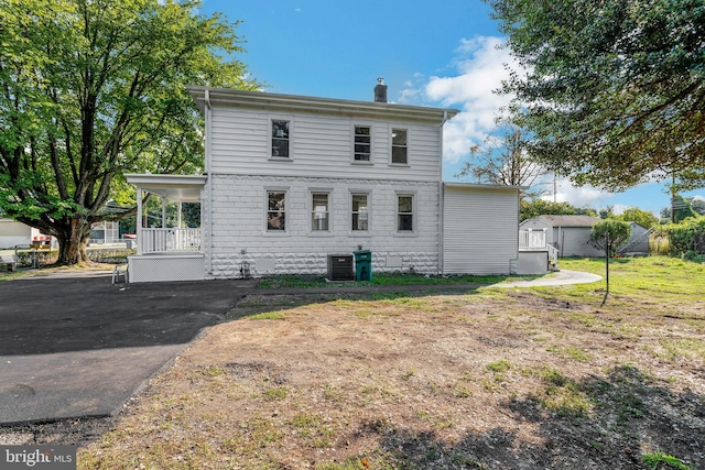 back of property featuring a lawn, a storage shed, and central AC unit