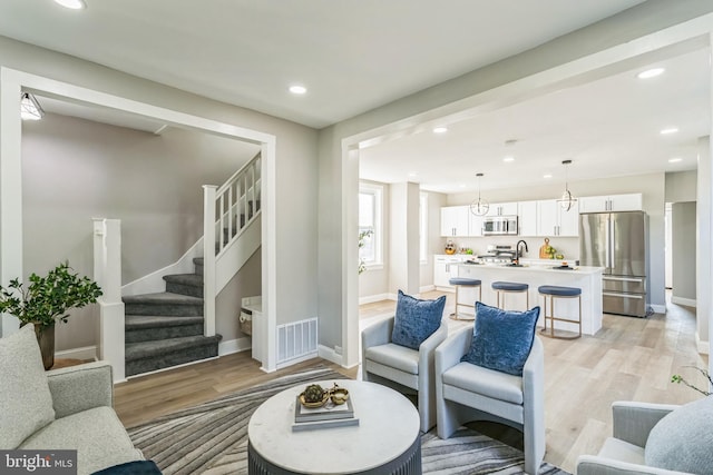 living room featuring a notable chandelier, light wood-type flooring, and sink