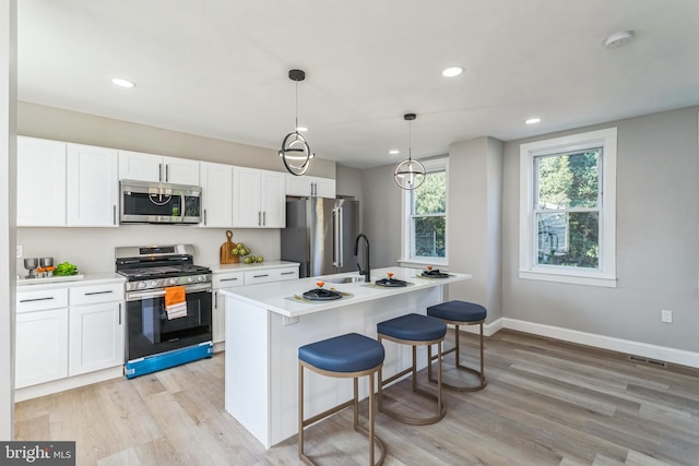 kitchen with stainless steel appliances, white cabinetry, decorative light fixtures, and a kitchen island with sink