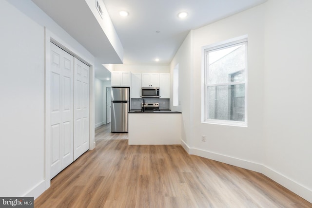 kitchen with light wood-type flooring, white cabinetry, sink, and stainless steel appliances