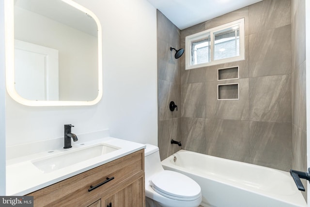 full bathroom featuring tiled shower / bath, vanity, and toilet