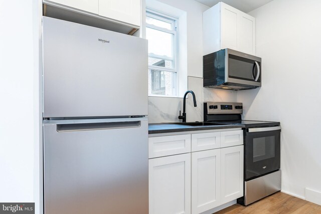 kitchen with light hardwood / wood-style floors, sink, stainless steel appliances, and white cabinets