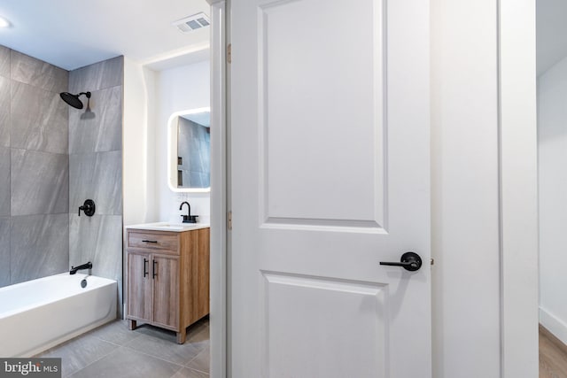 bathroom featuring vanity, tile patterned flooring, and tiled shower / bath