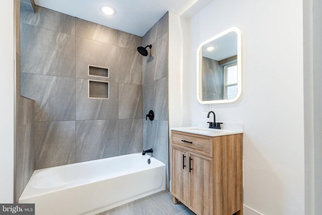 bathroom with tile patterned floors, tiled shower / bath combo, and vanity