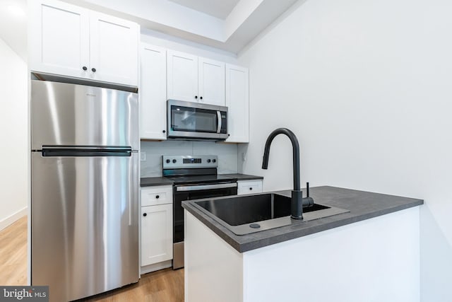 kitchen featuring light hardwood / wood-style floors, sink, white cabinets, decorative backsplash, and appliances with stainless steel finishes