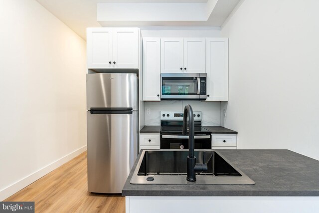 kitchen with stainless steel appliances, white cabinets, and light wood-type flooring