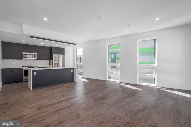 kitchen featuring appliances with stainless steel finishes, a kitchen island, decorative backsplash, and dark hardwood / wood-style flooring