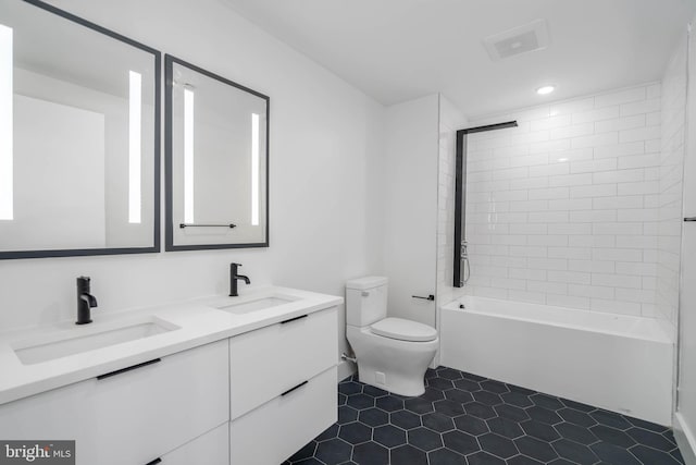 full bathroom featuring tile patterned flooring, toilet, tiled shower / bath combo, and vanity